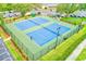 Aerial view of well-maintained tennis courts, enclosed by a fence, set in a landscaped community at 6250 Fairskies Dr, New Port Richey, FL 34655