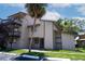 Condo exterior featuring a tan facade, green lawn and mature palm trees set against a blue sky with white clouds at 6338 Newtown Cir # 38A6, Tampa, FL 33615