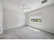 An empty bedroom with a ceiling fan, a window with blinds, and plush gray carpeting at 6447 Bradford Woods Dr, Zephyrhills, FL 33542