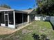 This shows a screened-in lanai along with a fenced-in backyard and fresh green grass at 7301 Mitchell Ranch Rd, New Port Richey, FL 34655