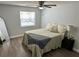 Comfortable bedroom featuring natural light, soft bedding, wood look flooring and ceiling fan at 7301 Mitchell Ranch Rd, New Port Richey, FL 34655