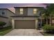 Home exterior featuring a well-maintained two-car garage, manicured lawn, palm tree against a lovely sunset at 7405 French Marigold Ave, Tampa, FL 33619