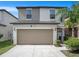 Inviting two-story home with a tan garage door, well-maintained landscaping, and a charming palm tree at 7405 French Marigold Ave, Tampa, FL 33619
