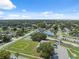 Overhead image capturing a community pool, green sports field, and recreational areas among a leafy neighborhood at 8897 54Th N St, Pinellas Park, FL 33782