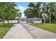 Inviting single-story home with lush green lawn, a long driveway, and mature trees at 8897 54Th N St, Pinellas Park, FL 33782
