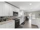 Bright kitchen with white cabinets, granite countertops, stainless appliances, and a dining area at 9105 Camino Villa Blvd, Tampa, FL 33635