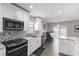 Modern kitchen featuring white cabinets, stainless steel appliances, granite counters, and wood-look tile flooring at 9105 Camino Villa Blvd, Tampa, FL 33635