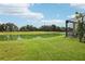 Expansive backyard with lush green grass, a serene lake view, and partial view of the screened lanai at 9107 Rally Spring Loop, Wesley Chapel, FL 33545
