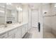 Elegant bathroom featuring double sinks, white cabinetry, and a tiled walk-in shower at 9107 Rally Spring Loop, Wesley Chapel, FL 33545
