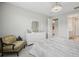 Bright bedroom featuring an elegant light fixture, chair and walk-in bathroom at 9107 Rally Spring Loop, Wesley Chapel, FL 33545
