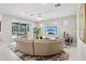 Bright living room featuring a large sectional sofa, a wall-mounted TV, and access to the outdoor pool area at 9107 Rally Spring Loop, Wesley Chapel, FL 33545