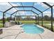 Private screened-in pool area with a lake view, lounge chairs, and an outdoor grill, perfect for entertaining at 9107 Rally Spring Loop, Wesley Chapel, FL 33545