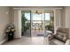 Living room view through sliding glass door of balcony with table and chairs, and serene lake at 10002 Key Haven Rd # 503, Seminole, FL 33777