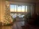 Festive living room with illuminated Christmas tree, sliding glass doors with view, and comfortable armchair at 10002 Key Haven Rd # 503, Seminole, FL 33777