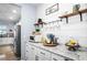 Bright coffee bar area with white cabinets, granite countertop, open shelving, and stainless steel appliances at 10624 Aldo Moro Dr, Wimauma, FL 33598