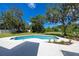 Backyard with a pool surrounded by a large patio, green grass and mature trees at 11203 Egret Nest Ct, Riverview, FL 33569