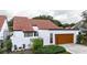 Charming home with a terracotta roof, white stucco walls, and a well-maintained front yard and a wood paneled garage door at 11501 Cerca Del Rio Pl, Temple Terrace, FL 33617