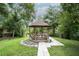 Outdoor gazebo with seating set in lush green yard and accessed by both stepping stones and traditional paver pathway at 11501 Cerca Del Rio Pl, Temple Terrace, FL 33617