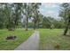Lush, green park area with mature trees and a walking path leading to the tennis courts at 11501 Cerca Del Rio Pl, Temple Terrace, FL 33617