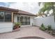 Brick patio with partial view of white home exterior with dark trim and some landscaping at 11501 Cerca Del Rio Pl, Temple Terrace, FL 33617