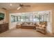 Bright sunroom with large windows, comfortable seating, and a ceiling fan at 11501 Cerca Del Rio Pl, Temple Terrace, FL 33617