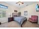 Cozy bedroom featuring a comfortable bed, nightstand, ceiling fan, and a pink upholstered chair at 11729 Newberry Grove Loop, Riverview, FL 33579