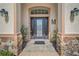 Elegant front door enhanced by stone columns, stylish lighting, and decorative accents at 11729 Newberry Grove Loop, Riverview, FL 33579