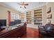 Inviting home office with custom built-in bookshelves, warm wood flooring, and a ceiling fan at 11729 Newberry Grove Loop, Riverview, FL 33579