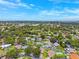 A neighborhood aerial showcasing the mature trees, blue skies, and nearby waterfront skyline at 12156 Meadowbrook Ln, Largo, FL 33774