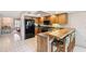 Kitchen features light wood cabinetry, an island with seating, and black appliances at 12156 Meadowbrook Ln, Largo, FL 33774