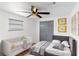 A cozy bedroom features a crib, a bed with gray bedding, a ceiling fan, and a window at 1328 Waikiki Way, Tampa, FL 33619