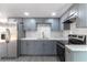 A well-lit kitchen features gray cabinets, marble backsplash, stainless steel appliances, and gray wood flooring at 1328 Waikiki Way, Tampa, FL 33619