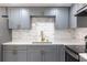 A well-lit kitchen features gray cabinets with gold hardware, marble backsplash, and stainless steel appliances at 1328 Waikiki Way, Tampa, FL 33619