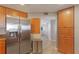 Bright kitchen with stainless steel fridge, wooden cabinets, and dining room in the background at 1340 Gulf Blvd # 16F, Clearwater, FL 33767