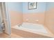 Brightly lit bathroom featuring a soaking tub with peach-colored tiling at 1370 Hill Dr, Largo, FL 33770
