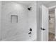 Modern bathroom features marble-look tile, matte black fixtures, and a built-in niche for a clean, spa-like aesthetic at 1586 Linwood Dr, Clearwater, FL 33755
