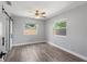A cozy bedroom featuring hardwood floors, a ceiling fan, and plenty of natural light from the two windows at 1586 Linwood Dr, Clearwater, FL 33755