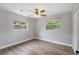 A simple bedroom with hardwood floors and light neutral paint with two windows for natural light and a closet at 1586 Linwood Dr, Clearwater, FL 33755