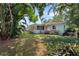 View of the lush backyard, featuring a well-maintained lawn and tropical foliage around the perimeter of the property at 1711 N Highland Ave, Clearwater, FL 33755