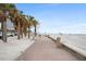 Picturesque view of the boardwalk, with sandy beach, palm trees, and cityscape of hotels under blue skies and scattered clouds at 1711 N Highland Ave, Clearwater, FL 33755