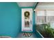 White front door featuring a glass window with a wreath, an exterior light fixture, and a welcome mat at 1711 N Highland Ave, Clearwater, FL 33755