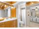 Well-lit bathroom with wood cabinets, sink, toilet and a shower with white curtain at 18093 Ohara Dr, Port Charlotte, FL 33948