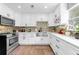 Modern kitchen with white cabinets, stainless steel appliances, mosaic backsplash, and ample counter space at 1893 Harding St, Clearwater, FL 33765