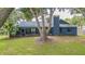 View of the home's backyard with a lush lawn, screened in porch, and mature trees providing shade at 23067 Brighton Pl, Land O Lakes, FL 34639