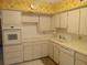 Kitchen with white appliances and cabinets, white countertops, and vintage yellow floral wallpaper at 2459 Franciscan Dr # 29, Clearwater, FL 33763