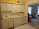 Bright kitchen with ample white cabinetry, appliances, floral wallpaper detail and tile floor at 2459 Franciscan Dr # 29, Clearwater, FL 33763