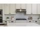 Well-lit kitchen featuring white cabinets, stainless steel appliances, and stylish backsplash at 2812 Long Bow Way, Odessa, FL 33556