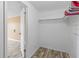 This open closet with woodgrain floors features a single hanging rod that is easily accessed from the adjoining bedroom at 3519 Richboro Dr, Holiday, FL 34691