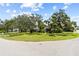 Exterior view of home on corner lot, surrounded by mature trees and lush landscaping at 358 Highland Shores Dr, Ellenton, FL 34222