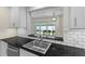 Kitchen with stainless steel sink and black countertops, overlooking a screened in porch at 358 Highland Shores Dr, Ellenton, FL 34222